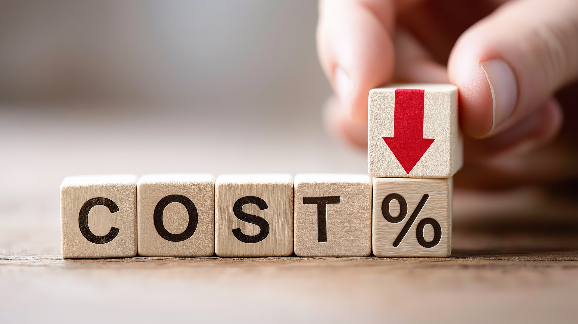 Cost of ISO 27001 certification in Australia illustrated by wooden blocks spelling COST with a downward arrow